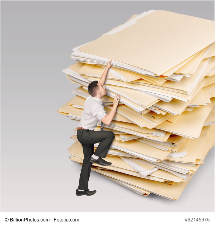 Mann erklimmt Papierberg Bild: Was sind die Vorteile der Digitalisierung?